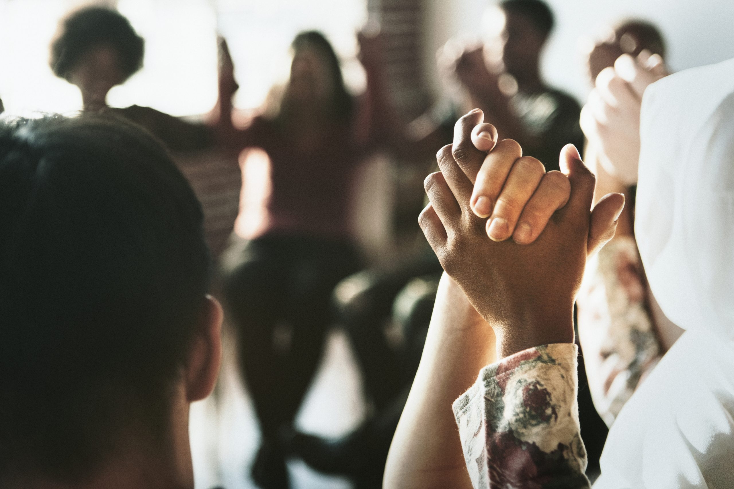 Group of diverse people holding hands up in the air